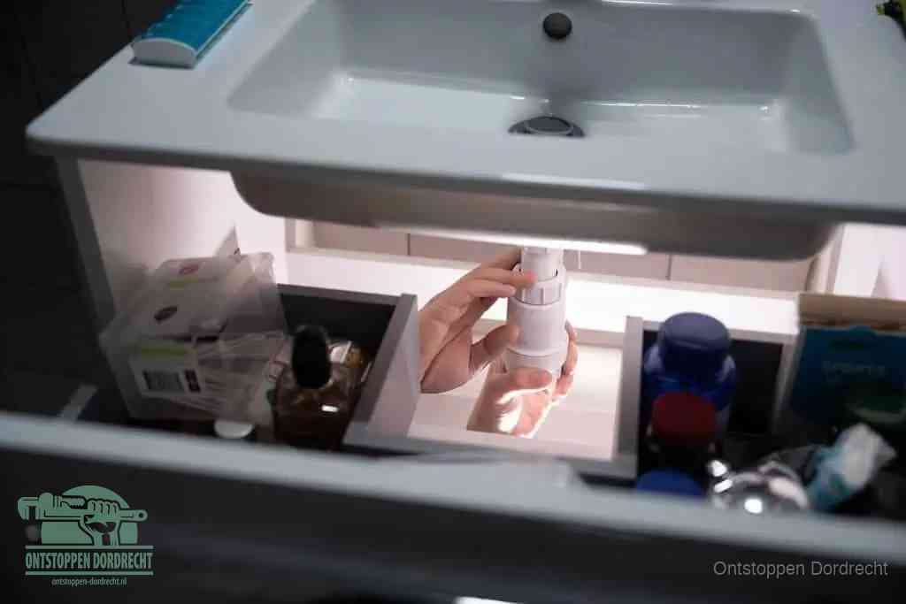 Een pompfles met zeep boven een wastafel, de heet water en afwasmiddel-methode om een vetprop in de afvoer los te maken in Dordrecht