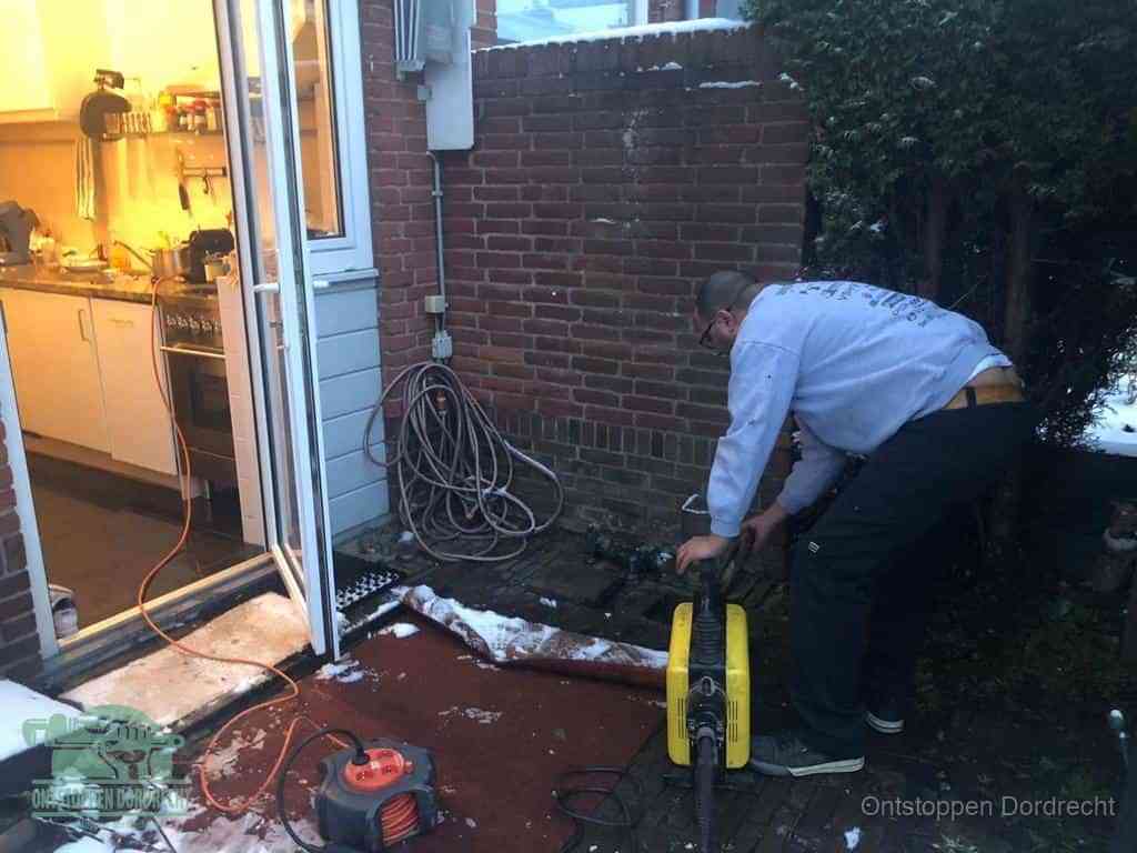 Een monteur werkt buiten bij een open riool-/grondput met een elektrische ontstoppingsmachine om een verborgen afvoerprobleem op te sporen in Dordrecht