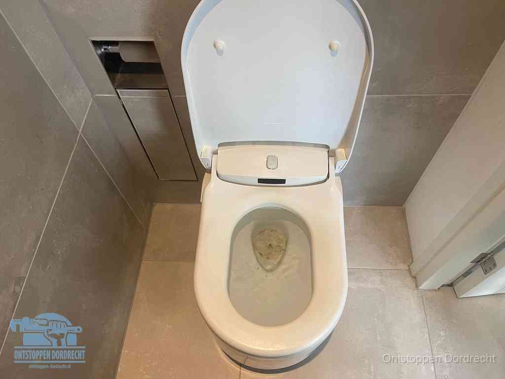 Een wit hangtoilet waarin een prop wc-papier op het water blijft drijven, een duidelijk signaal van een verstopte wc in Dordrecht