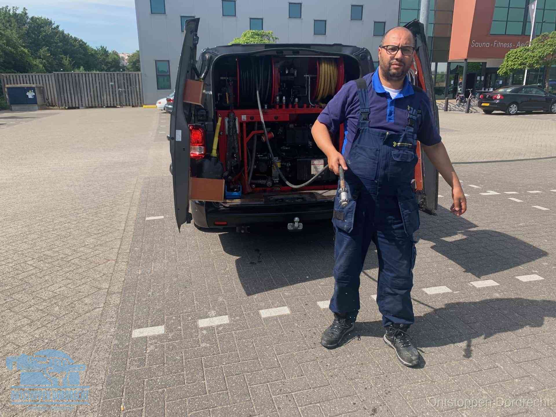 Een monteur bij zijn bestelbus met een hogedruk- en rioolreinigingsunit, klaar om de oorzaak van terugkerende wc-verstoppingen aan te pakken in Dordrecht