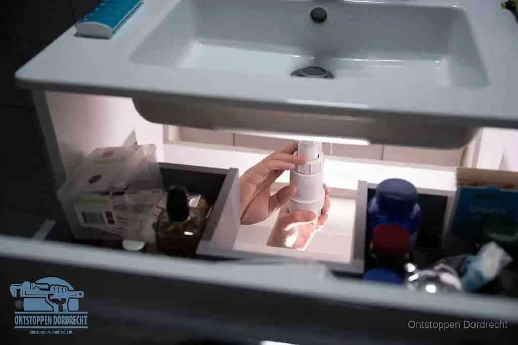 Een pompfles met zeep boven een wastafel in de toiletruimte, de warm water en afwasmiddel-methode om de wc te ontstoppen in Dordrecht