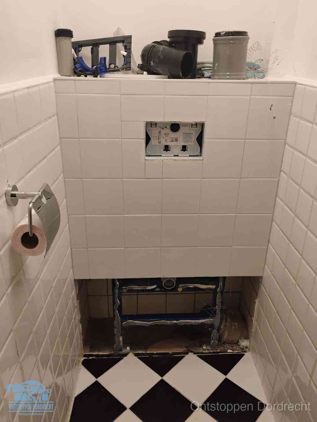 Een toiletruimte waar het hangtoilet en de inbouwreservoir-onderdelen zijn vrijgelegd voor onderhoud, periodiek nazicht voorkomt een wc-verstopping in Dordrecht