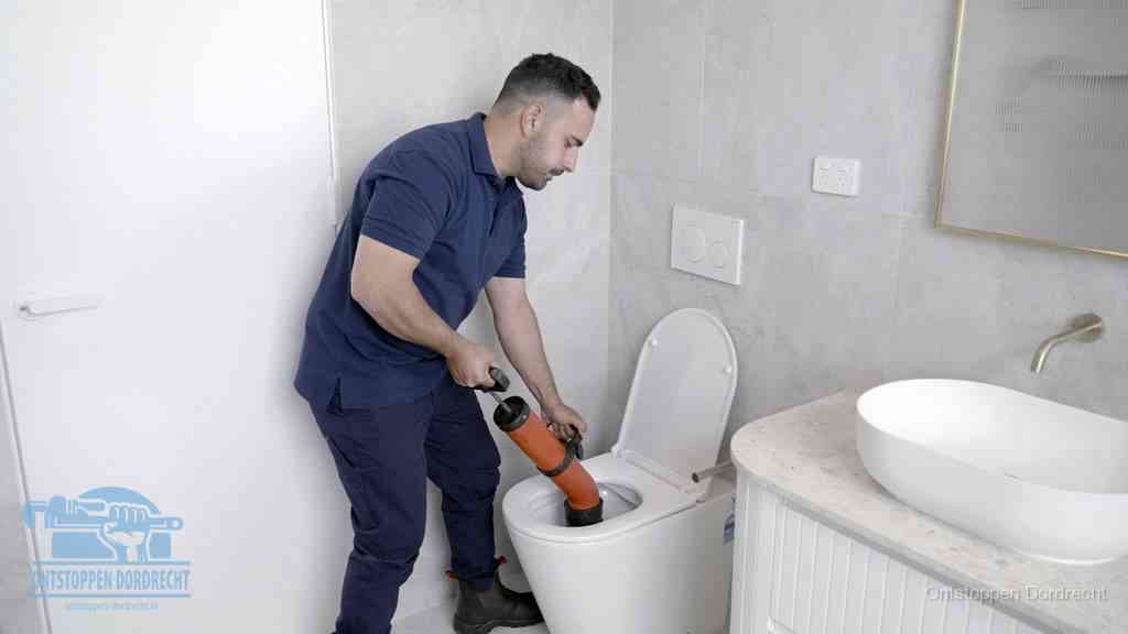 Een monteur gebruikt een handmatige perspomp (toiletontstopper) op een wandcloset tijdens het professioneel wc ontstoppen in Dordrecht
